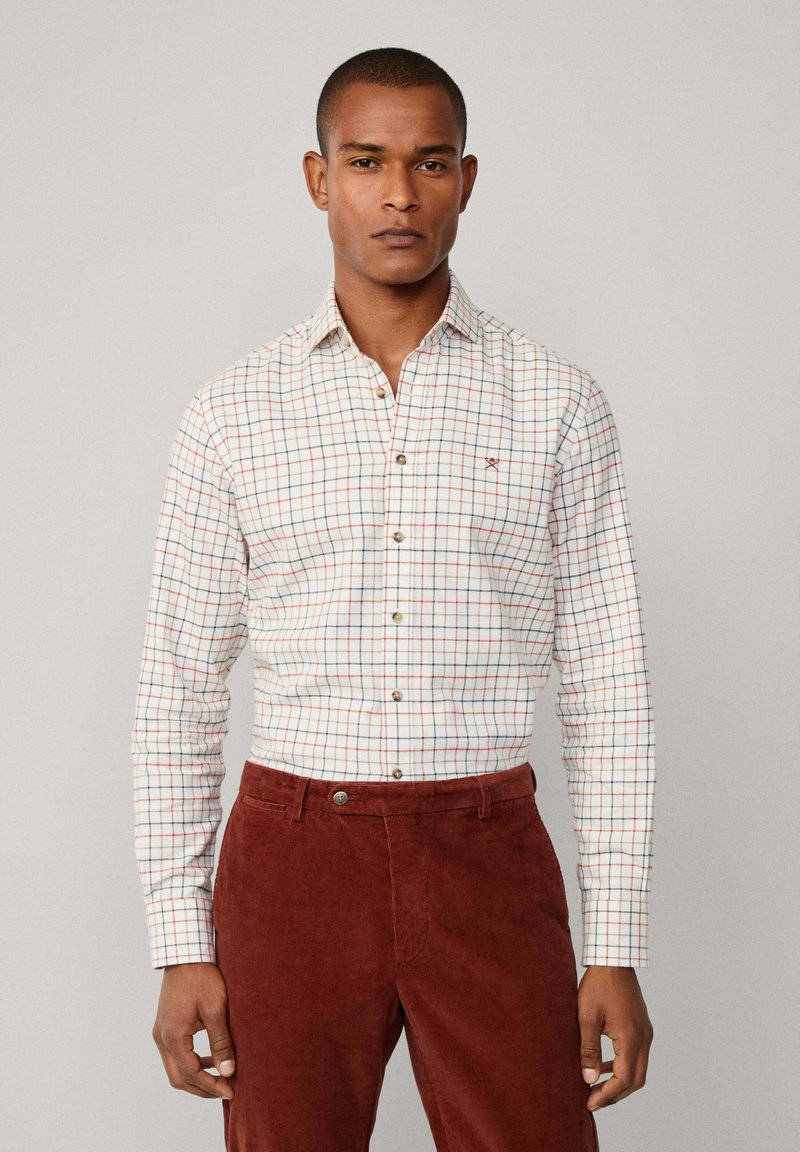 Witte button-up shirt met een rood en groen ruitpatroon, voorzien van knoopmanchet en een kleine geborduurde accent, gedragen met brown corduroy broek.
