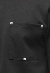 Fekete pulóver mellzsebbel, patentos záródással, sima, puha anyagból készült, letisztult dizájnnal.