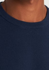 Navy Pullover mit strukturiertem Strick. Verfügt über einen Rundhalsausschnitt und gerippte Ärmelabschl�üsse, hergestellt aus einem weichen, atmungsaktiven Stoff.