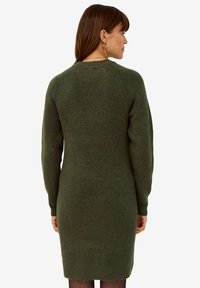 Grünes gestricktes Kleid mit langen Ärmeln, gerippter Textur und figurbetonter Silhouette, mit einem runden Ausschnitt.