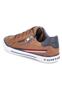 Sneaker basso marrone con lacci, cerniera laterale, toppa sul tallone blu navy, suola bianca con striscia blu navy e striscia rossa-bianca-blu laterale.