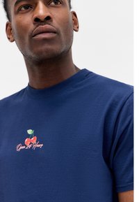 Navy blue cotton t-shirt with a crew neck, featuring an embroidered cherry graphic with the text "Open 24 Hours" in pink.