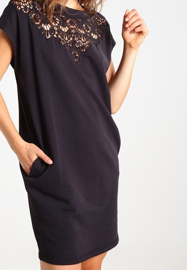 Robe noire avec un empiècement en dentelle, manches courtes, coupe décontractée et poches de chaque côté. Texture de tissu lisse.