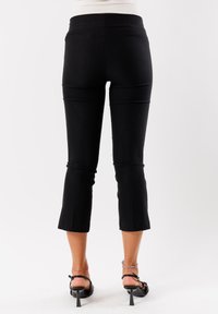 Pantaloni neri a vita alta con un design aderente, dotati di una cintura elasticizzata, leggere svasature all'orlo e una texture liscia e morbida.