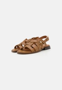 Sandales en cuir marron avec plusieurs brides entrecroisées, bout ouvert et un petit talon carré. Comprend une boucle latérale pour l'ajustement.