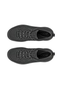 Zapatos deportivos negros con una superficie texturizada, acentos reflectantes y punta redondeada. Cuentan con un diseño de cordones y una lengüeta en el talón reforzada.