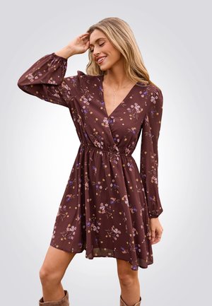 Braunes Blumenkleid mit langen Ärmeln, tiefem V-Ausschnitt, gerafftem Bund und schwingendem Rock. Mit mehrfarbigen Blumenmustern durchzogen.