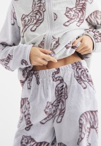 Szary zestaw dresowy z polaru z wzorem tygrysa, w skład którego wchodzi bluzka z zamkiem i spodnie na gumce. Miękka, pluszowa tekstura.