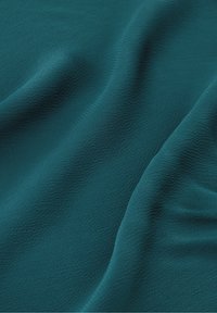 Teal gestructureerde stof met een lichte glans, met vloeiende krommingen en zachte plooien die de zachte, vallende kwaliteit benadrukken.