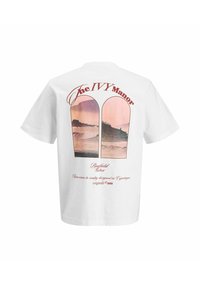 T-shirt blanc avec deux fenêtres en arc montrant un paysage côtier rose et violet, avec le texte « The IVY Manor » et « Bayfield Harbor ».