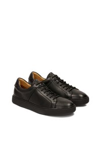 Zapatillas de cuero negro con acabado suave, puntera redonda y un interior en contraste en color marrón. Presentan cordones a tono y una suela de goma gruesa y texturizada.
