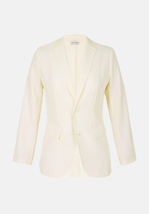 Világos sárga blézer, lekerekített hajtókával, két elülső zsebbel és gombos záródással. Simogató tapintású anyagból készült, strukturált szabással.