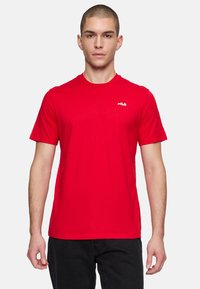 Rød kortærmet t-shirt med rund hals lavet af glat stof, der har et lille hvidt logo på venstre bryst; slank og tætsiddende design.