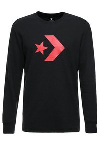 T-shirt noir à manches longues en tissu texturé, avec un grand logo étoile rouge et flèche sur le devant. Encolure ronde et coupe standard.