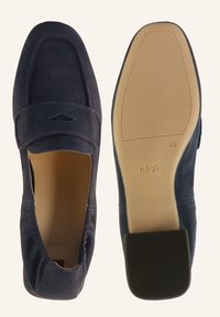 Navy suede slip-on shoes with rounded toe, stitched detailing, elastic panels on the sides, and a flat rubber sole. Brand logo on insole.