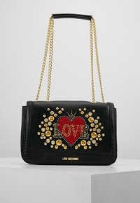 Svart Love Moschino-handväska med guldkedjesnor, röd hjärtform och guldnitar som stavar "LOVE" på framsidan.