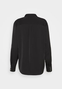 Chemise noire à manches longues, avec une texture lisse, des poignets à boutons et un ourlet arrondi. La vue arrière présente un design simple et épuré.