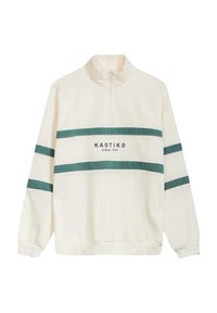Sudadera crema de media cremallera con rayas turquesa y el texto "KAOTIKO desde 1999" en el frente; textura suave, corte relajado.