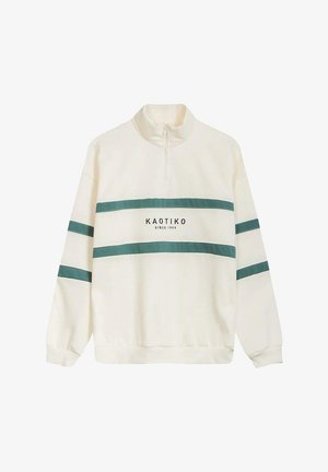 Sudadera crema de media cremallera con rayas turquesa y el texto "KAOTIKO desde 1999" en el frente; textura suave, corte relajado.