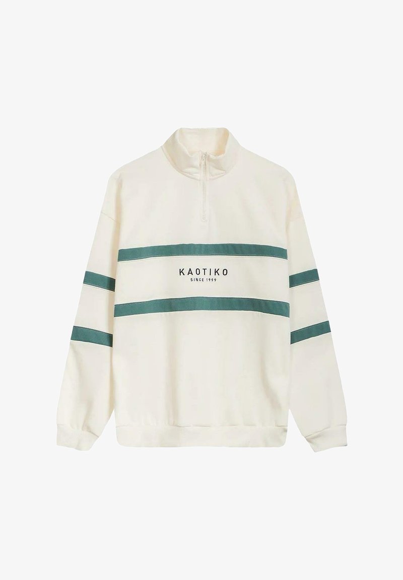 Sudadera crema de media cremallera con rayas turquesa y el texto "KAOTIKO desde 1999" en el frente; textura suave, corte relajado.