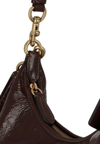 Dark brown leather handbag corner with gold metal rings and clasp attached to a leather strap, visible zipper along the edge.