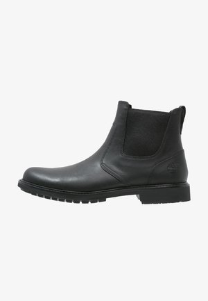 Bottines Chelsea en cuir noir avec des panneaux élastiques sur les côtés, bout arrondi et semelle en caoutchouc texturée. Présente un logo sur le talon.