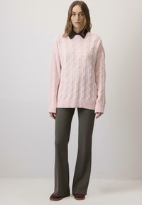 Pulover tricotat de culoare roz deschis, cu un croi lejer, asortat cu pantaloni evazați de culoare verde măsliniu și pantofi vișinii. Material texturat și manșete cu nervuri.