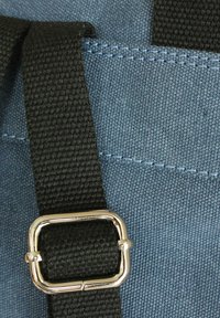 Leinenbeutel mit einem blauen Textilmaterial, schwarzem Gurt mit einer Metallschnalle und kontrastierenden blauen Nähdetails.