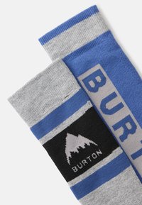 Modré a šedé ponožky Burton s čiernym akcentom a logom hory, s tučným textom na modrej časti. Pletená štruktúra so pruhovanými vzormi.