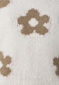 Maglione realizzato in tessuto a maglia, con una base bianca e modelli floreali marroni, superficie testurizzata e forme arrotondate nel design.