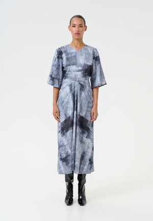 Gray and black abstract-print dress, V-neck, three-quarter sleeves, flowing design, paired with knee-high glossy black boots.