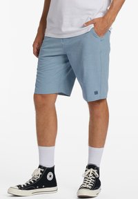 Light blue shorts made of textured fabric with a comfortable fit, featuring a side pocket and a small logo patch near the hem.