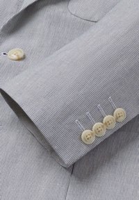 Rukav svijetlosivog odijela na prugice s četiri bež dugmeta i detaljnim umetkom na manžetni.