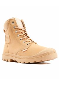 Botas altas de gamuza en color marrón claro con un parche redondo de logo, ojales de metal, diseño con cordones y una suela de goma texturizada.