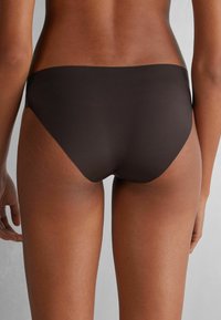 Brun bikiniunderdel i mjukt tyg, med en minimalistisk design och låg midja, med rena linjer och inga synliga mönster eller detaljer.