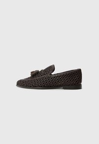 Brown woven slip-on shoe with a smooth leather accent and tassel detail, featuring a low profile and flexible sole.