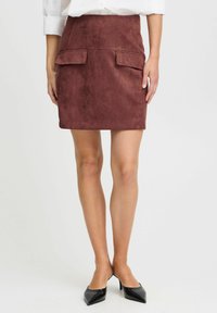 Roter Kunstwildlederrock mit tailliertem Bund und zwei vorderen Klappentaschen. Das Design ist gerade mit einer glatten Textur und gesäumten Kanten.