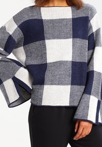 Granatowy i biały, oversize'owy sweter w kratę, z szerokimi rękawami i pudełkowym fasonem, wykonany z teksturowanej dzianiny.
