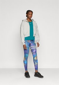 Γκρι φούτερ cropped, πετρόλ κορυφή και πολύχρωμοι floral κολάν με απαλή υφή. Μαύρα αθλητικά παπούτσια ολοκληρώνουν την εμφάνιση.