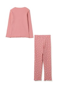 Blusa de algodón rosa de manga larga con dobladillo de volantes, combinada con leggings rosa a juego que presentan pequeños patrones de corazones de color rosa claro.