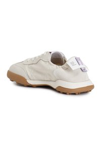 Sneaker beige chiaro con tomaia in suede e tessuto, suola ammortizzata e suola in gomma testurizzata con tacchetti di trazione visibili.