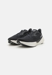 Baskets de sport noires avec une tige texturée, fermeture à lacets et semelle intermédiaire blanche contrastante. Présente une silhouette élégante et un motif de semelle en caoutchouc.