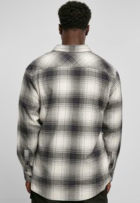 Rutet flannel skjorte i sort og hvid, med en button-down krave, lange ærmer og en afslappet pasform med en let buet nederste kant.