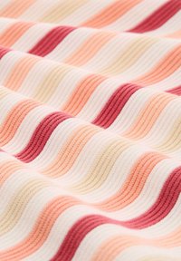 Textiel met golvende lijnen in roze, perzik en crèmekleur, met een gestructureerd ribbelpatroon dat een gelaagd visueel effect creëert.