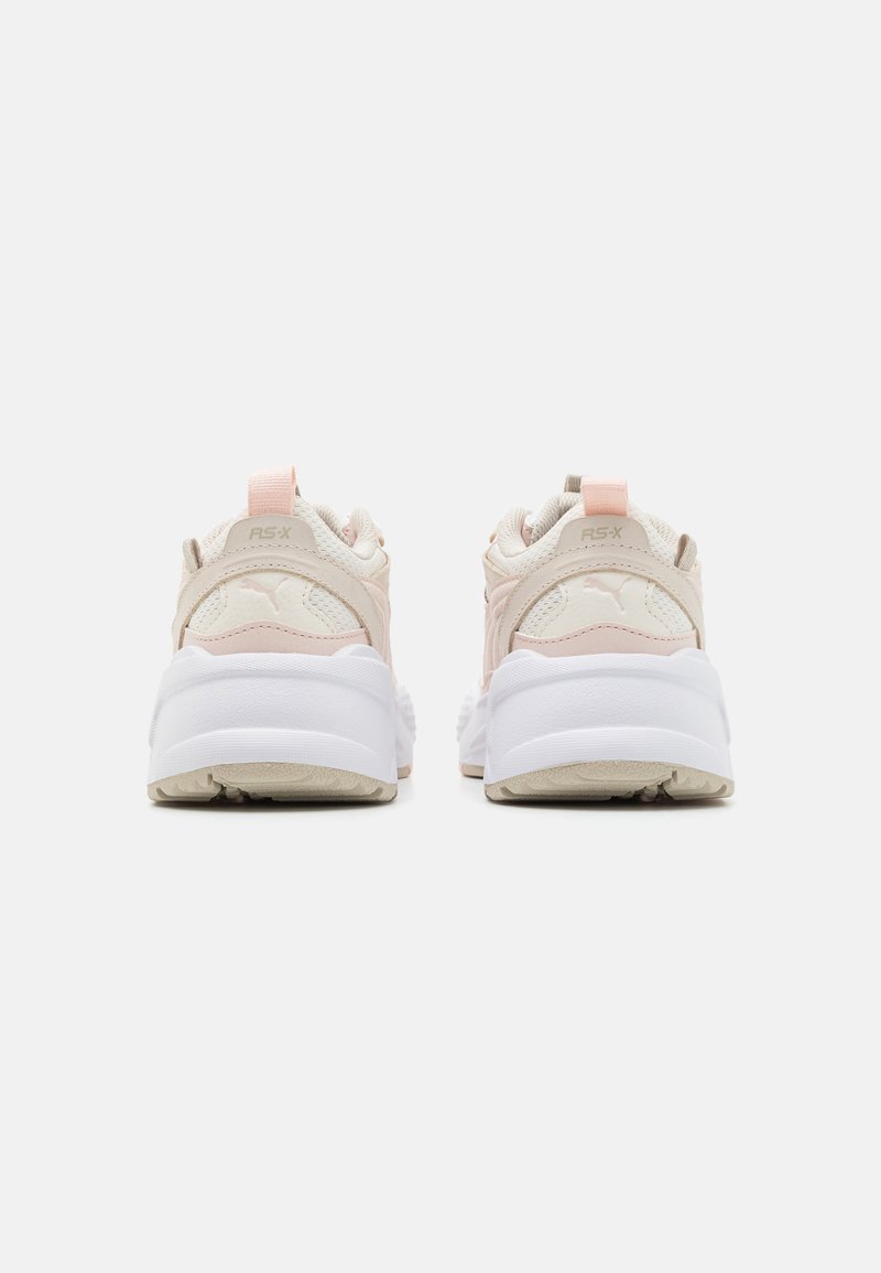 Rosa- und cremefarbene Sportschuhe mit einem strukturierten Obermaterial, gepolstertem Schaftrand und einer dicken weißen Gummisohle. Mit einem Logo an der Ferse.