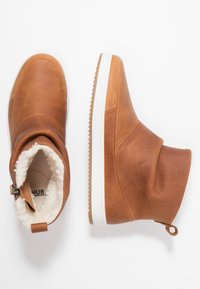 Botas de tobillo de cuero marrón con suela de goma blanca, acabado texturizado y forro suave. Cuenta con una cremallera lateral y una lengüeta trasera para facilitar su colocación.