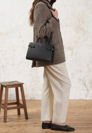 Borsa a tracolla nera in pelle con manici superiori e tracolla regolabile. Superficie texturizzata con hardware minimale, forma rettangolare. Abbinata a un cappotto in tessuto a scacchi.