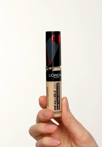 L'Oréal Paris Infallible concealer i en klar tub, med ett svart och rött lock, som visar en beige formel och en smal applicator.