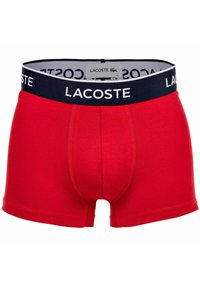 Röda bomullsboxer med en marinblå elastisk midja som har "Lacoste"-logotypen. Sl ät textur och en åtsittande design, lämplig för vardagsbruk.