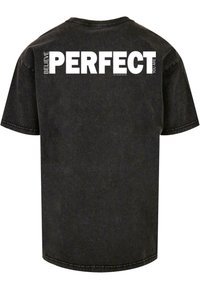 Camiseta de algodón negra con mangas cortas, que presenta un gran texto blanco en la parte posterior que dice "CREE PERFECTO QUE ERES". Textura suave, ajuste informal.